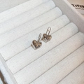 Détail macro de boucles d'oreilles cœur argentées à texture métal liquide sur boîte - Crochets de boucles d'oreilles / Argenté