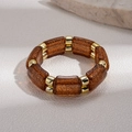 Nahaufnahme von Bernstein-Acryl-Gliedern und Goldperlen auf einem elastischen Armband - Dunkelbraun