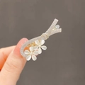 Elegant gold hair claw with white rhinestone flowers and opal stones in hand view - Romantic Bouquet Hair Clip