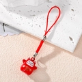 Japanese lucky cat phone charm with red bell and woven cord on textured surface - Red Treasure