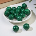 Polished green malachite spheres with black swirl patterns in a white ceramic bowl - Malachite