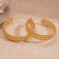 Close-up of 18K gold plated C-shaped hoop earrings with intricate woven texture on stone - Gold
