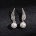 Dettaglio di orecchini a ala in argento con strass scintillanti e perle bianche rotonde - Orecchini di Perle con Ali e Ago d'Argento