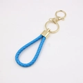 Porte-clés en cuir tressé bleu avec boucle et anneau en métal doré sur fond blanc - Bleu