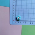Close-up of a blue and pink resin frangipani flower accessory on a measuring mat - Blue