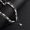 Detalle del colgante de fantasma plateado y collar de perlas blancas sobre textura negra - Collar de Fantasma de Varias Capas