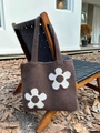 Detail of a brown knitted tote bag featuring large white floral patterns on a wooden chair - Dark Brown