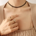 Retro gold collar and black gemstone rings set on a model in beige knitwear - Black Zirconia Necklace