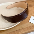 Detail of dark brown pleated leather headband with neat stitching on a beige ceramic plate - Brown