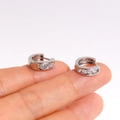Kleine silberne Creolen mit Zirkonia-Besatz, präsentiert auf einer Fingerspitze - Einheitsgröße / Ohrringe / Weißgold