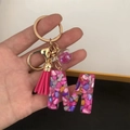 Macro view of resin letter M keychain with pink tassel and gold hardware detail - Small Ball Tassel Clasp / M