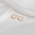 Macro detail of gold hoop earrings with vibrant colorful enamel dots on white silk - Colorful