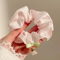 Detailed close-up of pink floral scrunchie with green ribbon bow and flower pendant - Matte Flower Charm Style / Purple Orange Floral Print