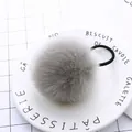 Detailed view of a soft grey fluffy pom pom hair tie on a white ceramic display tray - Grey Pom Pom 5cm