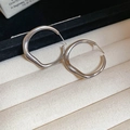 Gros plan de boucles d'oreilles créoles irrégulières en argent dans un écrin à bijoux beige - Argenté