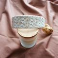 Detailed close-up of a woven beige and white raffia headband on brown pleated fabric - Cream Checkered