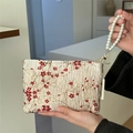 Detailed close-up of champagne makeup bag with red plum embroidery and pearl handle - Red Plum Blossom