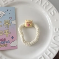 Détail d'un chouchou blanc avec un ours jaune tenant une fraise dans un plat blanc - Cube