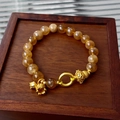 Detailed close-up of amber crystal beaded bracelet with gold flower charms on a wooden tray - 5# Gold Zircon Hulu