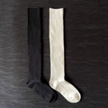Detail of ribbed knit texture on black and cream over-the-knee socks laid on wood - Over-knee Black