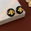 Detailed macro view of vintage golden bee earrings on a black round enamel base - Silver Earring Post Round Bee Enamel Stud Earrings