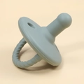 Detail view of a soft grey-blue silicone baby pacifier with textured handle and matte finish - Grey Green