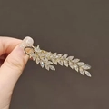 Elegant gold leaf branch hair clip with sparkling crystals held in hand - Golden Wheat Ear