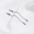 Macro detail of silver extension chains with lobster clasps and heart charms on silk - White Gold Color 3D Heart