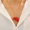 Detalle de un collar de cadena dorada con dos colgantes de fresas rojas en una modelo - Dorado (Collar de Fresa)