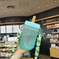 Creatieve cyaan ijsvormige waterfles met kleurrijke schouderband vastgehouden in een café - 300ml / Blauw