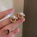 Pendientes de botón dorados de doble lazo con perlas blancas sostenidos en la mano - 38# Perla Poste de Plata