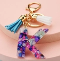 Detailed view of resin letter K keychain with colorful glitter and blue white tassels - Letter K