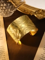 Nahaufnahme des breiten goldenen Bohemian-Armreifs mit ethnischen Vintage-Prägemustern - Augenmuster Gold