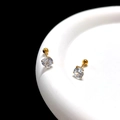 Macro detail of clear zircon stud earrings with golden screw back on white porcelain - 7mm / Gold