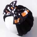 Detail van Halloween gebreide babymuts met een grote strik voorzien van botten en pompoen - Zwart