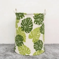 Large cylindrical laundry basket with green monstera leaf pattern and sturdy white handles - Monstera