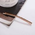 Dettaglio del fermaglio per capelli oro rosa con strass ambra su una rivista - Base Oro Rosa Strass Marrone