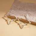 Detail of silver star-shaped earrings with hollow frame on a natural stone surface - Silver