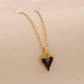 Gros plan sur la chaîne dorée et le pendentif cœur noir brillant sur fond beige doux - Noir