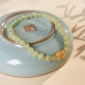 Detalle de pulsera de cuentas de jade verde claro con amuleto dorado en un cuenco de cerámica - Pulsera de Jade Hetian (Caja de Regalo Exquisita)