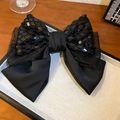 Dettaglio di un grande fiocco di pizzo nero con paillettes e mesh su vassoio - Clip a molla con fiocco nero