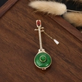 Chinese lute brooch with green jade ring and red stone on dark wood display - Red Stone Pipa