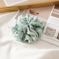 Detail of light green ruffled scrunchie with bead trim on a white fabric background - Pleated Light Green