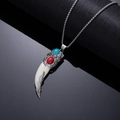 Macro detail of retro wolf tooth pendant with red gemstone and turquoise inlay on silver chain - White Animal Tooth Carved with Red and Blue Turquoise