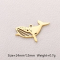 Macro detail of a golden whale-shaped stainless steel pendant on textured paper - Whale / Gold