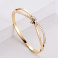 Crossed golden stainless steel bangle featuring sparkling micro-pave crystals and secure clasp - Golden Knot Rhinestone Style (4894576064538)