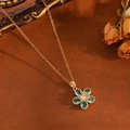 Gros plan détaillé du pendentif fleur dorée avec gemmes bleues sur chaîne fine dorée - Collier Fleur en Zircone Bleue Dorée