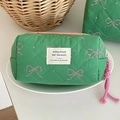 Close-up of green quilted makeup bag with pink bow patterns and a woven logo patch - Green Fruit Bow [Octagonal Bag]
