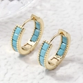 Pendientes dorados con piedras azul cielo y textura de cuentas sobre fondo blanco - Zirconia Turquesa Dorada