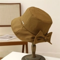 Dark khaki bow bucket hat with a silver metal plaque on a vintage wooden stand - M (56-58cm) / Camel